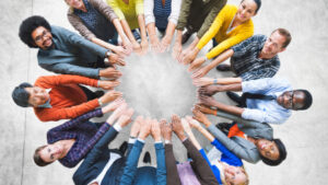 diverse group of people extending hands in circle looking to camera above - teamwork